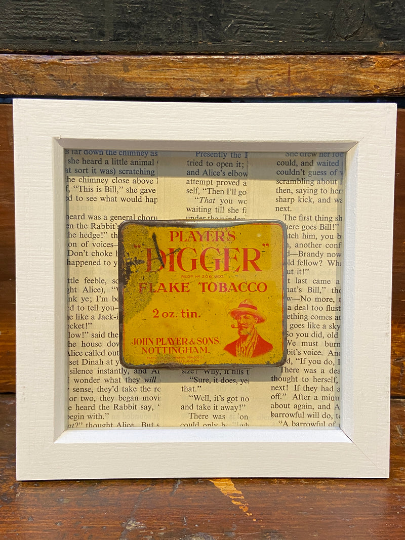 Vintage ‘Players Digger Flake Tobacco’ tin framed with vintage Alice in Wonderland book text. By Lost and Found Projects.